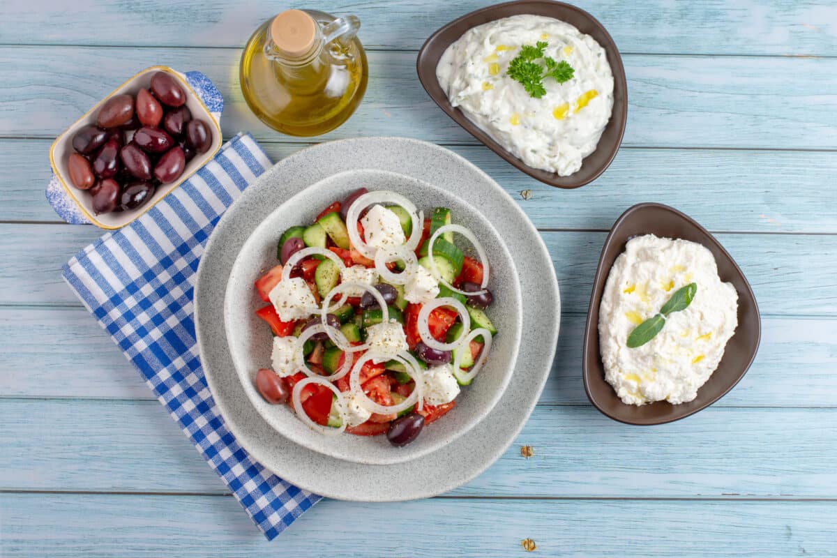 Greek salad with tzatziki, olives and feta cream. Traditional salad, meze,  with olive oil, flat lay